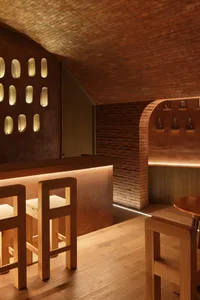 Warm and inviting bar area with a counter, stools, and bottles on display