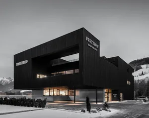 A large modern building with a black exterior and a prominent glass wall, set in a contemporary urban environment