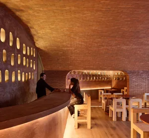 A cozy bar with a brick wall, chairs, and a counter for ordering drinks
