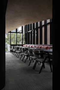 A modern restaurant with wooden tables and chairs, dimmed lighting, and a cozy atmosphere