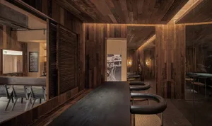 A cozy bar area with a wooden table surrounded by black leather chairs, creating a warm and inviting atmosphere