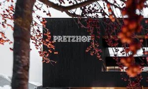 Modern building with a black exterior, large window, and potted plants, conveying urban design and functionality