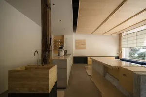 Empty restaurant kitchen with a wooden countertop, two sinks, a refrigerator, and a microwave, with various bottles scattered throughout the space, giving a clean and well-organized appearance