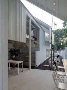 A modern living-dining space with white walls, wooden furniture, and a relaxed atmosphere, featuring a person sitting on a chair