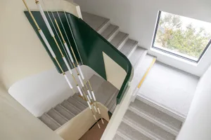 A modern staircase with a white wall and grey steps in a residential building