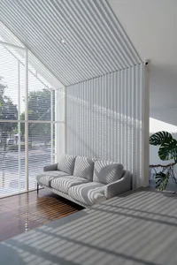Open living area with a striped sofa, vertical blinds, potted plants, and a chair, featuring natural light and a simple atmosphere