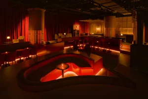 A luxurious restaurant interior with red velvet curtains, multiple chairs, a dining table, and a couch, exuding comfort and sophistication