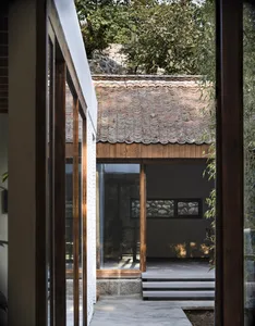 Open living area with wooden walls, floors, and two windows providing natural light