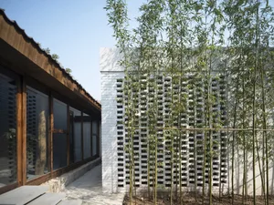 A modern house with a white exterior and a bamboo fence in front, featuring symmetrical windows and a clean design