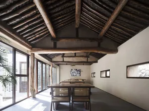 Cozy dining space with a wooden ceiling, a dining table, and four chairs, dimly lit for a warm ambiance