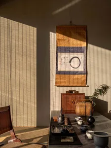 Dimly lit Asian-inspired living area with a dining table, chairs, decorative tapestry, and traditional-chic decor