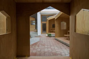 Warm and inviting open concept living area with a brick floor, wooden walls, chairs, a dining table, and a potted plant