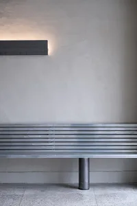 A metal bench in an outdoor public space, possibly near a building or a park