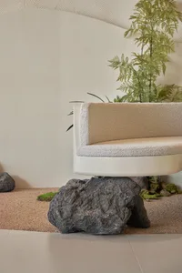 A serene indoor space with a concrete bench surrounded by potted plants, creating a calming atmosphere