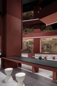 A modern restaurant interior with a large dining table, black countertop, red walls, and a sink area