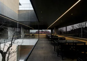 Modern restaurant interior with a large dining area, potted plants, and sleek furniture