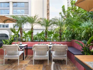 Outdoor dining area with wicker chairs and tables, umbrellas providing shade, and a relaxed atmosphere