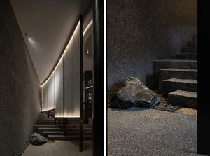 Contemporary building with black stone wall and metal railing, featuring a staircase and sleek design