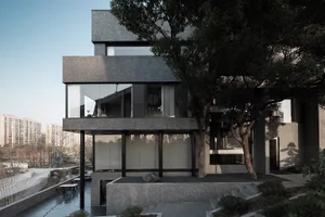 A modern building with gray stone walls and black glass windows, set against a backdrop of trees in an urban environment