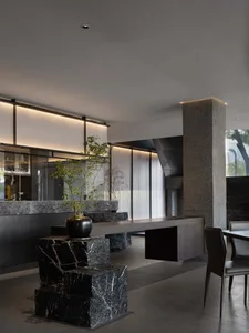 Elegant restaurant space with a stone wall, marble countertop, chairs, and a potted plant, featuring high-quality materials and design elements