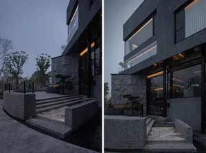 Exterior building facade at night with concrete walls, steps, and a staircase, set against a dark background