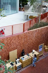 A casual indoor space with a brick wall, people standing and sitting at tables, and a relaxed atmosphere