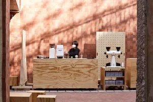 A casual coffee shop interior with a wooden counter, cups, a bowl, and bottles, inviting atmosphere