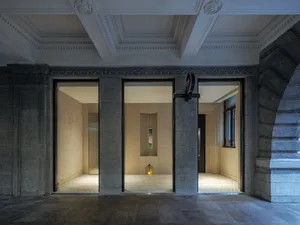 Interior of a modern hotel room with a bathroom and hallway, featuring clean lines, minimal decoration, and bright lighting