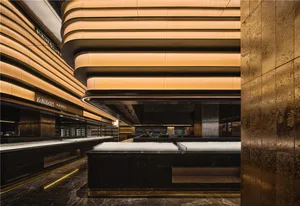 Spacious hotel lobby with high ceilings, gold accents, and modern design, featuring seating areas and dining tables