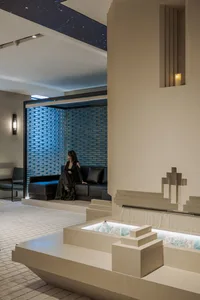 Comfortable living area with a stone-textured wall, a couch, two chairs, and a person relaxing