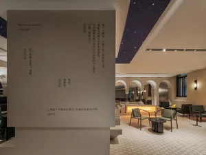 Calm and inviting lobby with stone walls, chairs, and a dining table, perfect for gathering and relaxation