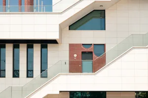 A multi-level building with white walls and red brick elements, featuring stairs and a mix of residential and commercial spaces