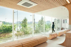 Open modern living area with wood furniture, large windows, and natural light