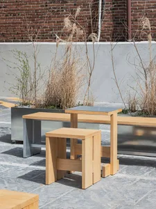 A relaxed outdoor patio area with two wooden benches, potted plants, and a concrete surface