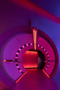 A futuristic interior space with a spiral staircase, pink and purple walls, and red lights on the staircase