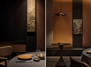 Upscale restaurant dining area with two tables, chairs, a painting of a mountainous area, and various tableware