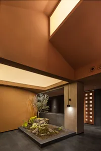 A cozy open space with a brown ceiling, featuring a bench, potted plants, and a clock on the wall