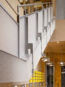 A well-lit staircase in a hotel with wooden steps and metal railings, illuminated by several lights along the stairwell