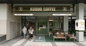 A green and white themed coffee shop with chairs and dining tables, inviting atmosphere, and a woman walking in