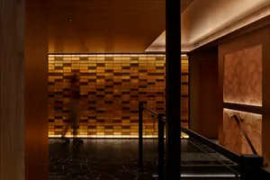 A calm hallway with a wooden door and wooden wall panels, two people walking down the hallway