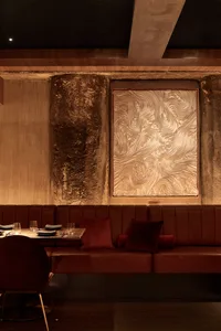 A modern restaurant interior with wooden walls, multiple tables, chairs, and couches, creating a warm and inviting atmosphere