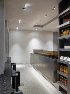 Industrial kitchen with concrete walls and floors, dimly lit with a counter and display case filled with food items