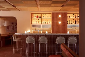 A cozy bar area with a marble counter, multiple bottles, and comfortable seating for patrons