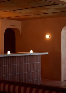 Modern kitchen with cement walls, two light sources, and a doorway