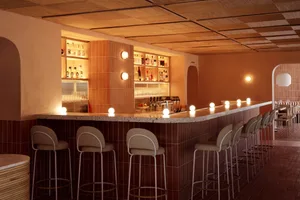 A cozy bar area with a long wooden countertop, chairs, and a warm atmosphere, perfect for socializing and enjoying drinks