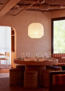 Warm and inviting restaurant interior with a round table, chairs, and wood elements, featuring wine glasses and a cozy atmosphere