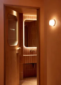 A simple bathroom with brown tiled walls, a sink, toilet, and mirror, creating a warm atmosphere