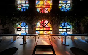 Warm and inviting cafe space with stained glass window, multiple tables, and natural light