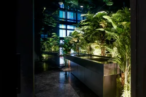A serene bathroom space with a metal sink surrounded by multiple potted plants, creating a peaceful atmosphere