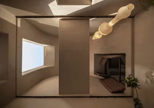 Empty modern living area with a large window, natural light, and two potted plants
